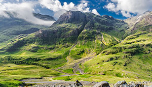 A scenic landscape featuring lush green mountains under a partly cloudy sky, showcasing the natural beauty of the outdoors.